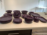 Full set laid out on countertop showing stacks of plates, bowls, mugs and serving pieces.