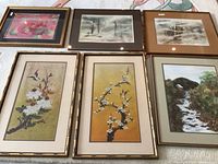 Group view of all six framed pieces laid flat, showing different nature and abstract themed watercolours and prints, various frame styles and sizes