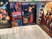 Six large movie poster boards with themes from Harry Potter, Rent, Moulin Rouge, Sahara and others arranged upright on floor.
