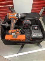 Soft tool bag containing drill, two batteries, charger and case