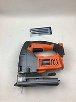 Full view of orange and gray Ridgid cordless jig saw with black grip and extra blades.