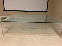 Front angle view of the rectangular coffee table showing Lucite sides and glass top.