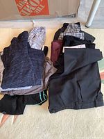 Photo showing dark gray and light gray sweaters folded alongside black and checkered patterned pants.