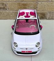 Top front view of white 2008 Barbie Fiat car with pink interior, showing transparent roof and Barbie branding on front.