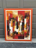 Front view of the large rectangular abstract painting on canvas with orange frame border, placed in front of a garage door.
