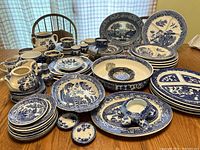 Wide view of the entire porcelain lot including plates, pitchers, cups, saucers, serving platters, and condiment dishes. Shows the blue and white patterns clearly with some pieces stacked.