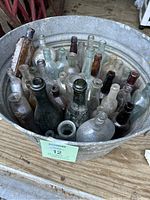 Oblique view of galvanized bucket filled with assorted old glass bottles showing colors and neck shapes