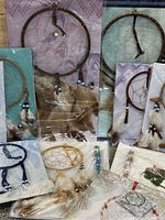 Photo showing 11 individual packaged dream catchers with wooden hoops, feather and bead decorations, different colors and sizes.
