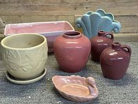 Seven assorted mid-century American art pottery pieces shown together on carpet.