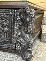 Close-up of ornate horse head foot supporting the decorative chess box, showing carved details and wear.