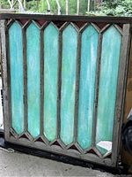 Front view of the old slag glass window showing blue/green vertical panels with raspberry colored diamond edge glass and chipped paint on the frame.