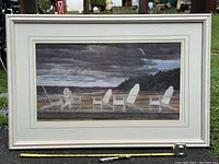 Framed print of Adirondack chairs on a wooden dock by the beach with a stormy, cloudy sky.