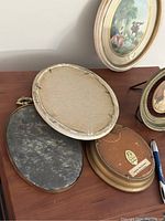 View of back sides of five oval frames showing their backing materials and condition.