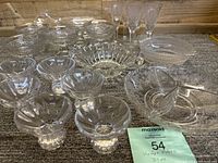 Photo showing the full assortment of 21 vintage clear glass pieces including bowls, dishes, and glasses arranged on a surface, accompanied by a lot note.