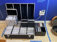 Five storage containers for DVD and CD media, various sizes and materials, organized and filled with discs or sleeves.