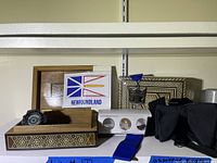 Wooden boxes with inlay, souvenir Newfoundland plaque, coins in case, medal with blue ribbon on shelf