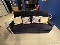Front view of navy blue upholstered recliner sofa with four cushions placed on the seats.