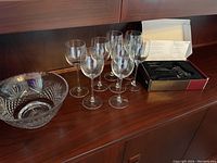 Full lot showing lead crystal bowl, 8 crystal wine glasses, and boxed corkscrew on wooden cabinet