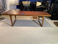 Full view of mid-century modern coffee table showing rectangular top and sled-style legs.