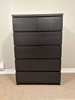 Front view of the dark brown IKEA highboy dresser showing five drawers and flat top.