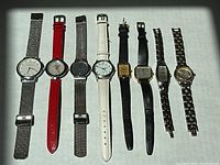 Eight ladies dress watches laid out in a single row showing variation in straps and dial shapes.