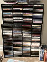 Photo showing large collection of vertically stacked music CDs and DVDs in jewel cases on shelving unit.