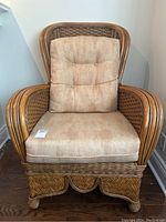 Front view of rattan wicker lounge chair showing beige cushions, armrests and base.