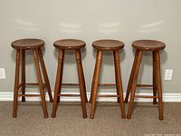 Front view of four bar stools together against wall