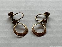 Top-down view of the screw back earrings showing engraved details on the circular hoop sections.