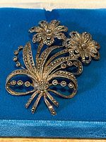 Close-up of the vintage sterling silver floral brooch showing intricate design with marcasite stones on blue felt.