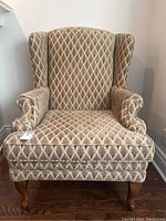 Front view showing diamond pattern upholstery, rolled arms, and wooden cabriole legs.