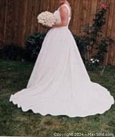 Full view of the dress worn outdoors showing the skirt and train spread on the grass.