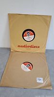 Two 16-inch records in their original 'audiodiscs' paper sleeves, showing front view with label visible through hole.