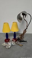 Photo of three vintage desk lamps as described, showing the metal lamp with twisted fabric cord and the pair of colorful lamps.