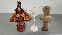 All three figures in the lot visible side-by-side: vintage Prague doll in ornate clothing, distressed white metal ballerina, and carved wooden fish with fins raised.