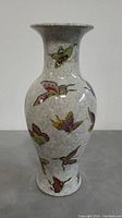 Full frontal view of ceramic vase with visible multi-colored butterflies and crackle glaze on off-white background.