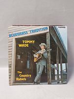 Album cover of Tommy Wade - Bluegrass Tradition featuring a man standing on porch with guitar