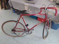 Full side view of the Raleigh Concorde bike showing red steel frame, saddle, handlebar with red tape, tires, and wheels.