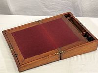 Top angled view showing maroon felt writing surface, wooden frame, and top compartments.