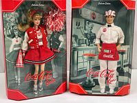 Front view of Barbie and Ken Coca Cola collector edition dolls in original boxes, showing detailed presentation and branding.