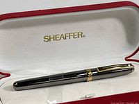 Sheaffer fountain pen resting in white padded interior of red presentation box, Sheaffer logo visible inside lid.