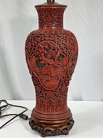 Full front view of the vintage carved cinnabar resin lamp showing the detailed openwork carving and wooden base.