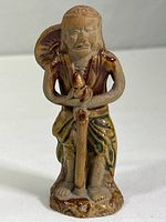 Front view of the small terracotta figure, showing full body, standing pose, and detailed facial expression.