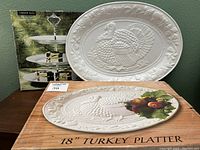 Photo of the white ceramic 18-inch turkey platter with embossed turkey design next to its original box.