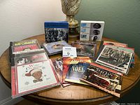 Multiple music CD cases arranged on a wooden table showing various genres like big band and Christmas music.
