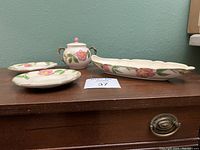 Four-pieces of Franciscan Desert Rose pottery set displayed on wooden surface including two saucers, sugar bowl with lid, and oval serving dish
