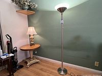 Full view of the LED floor lamp standing 69 inches tall next to an end table and a smaller lamp, showing its size and style.