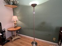 Full view of the LED floor lamp standing next to a small table and lamp, showing height and design.