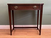 Front view of mahogany side table showing drawer and tapered legs