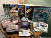 Full view of table displaying numerous vintage audio cassette tapes and boxed sets of old time radio shows.